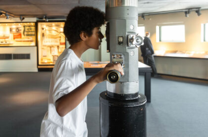 A young boy looks through a World War II era TANG periscope at MOHAI.