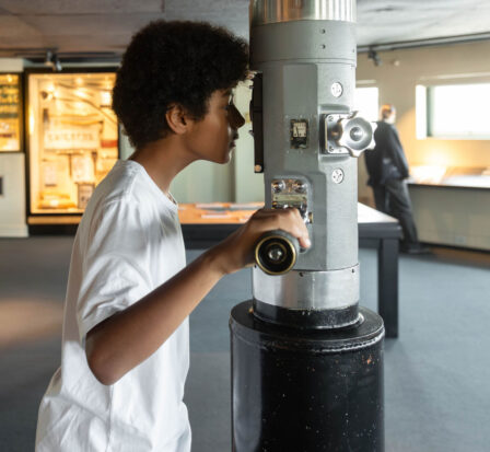 A young boy looks through a World War II era TANG periscope at MOHAI.