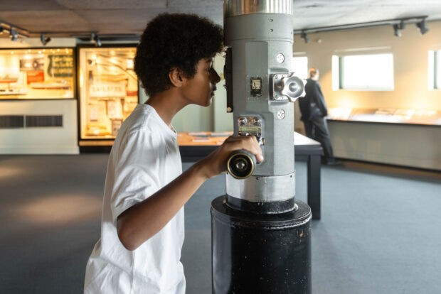 A young boy looks through a World War II era TANG periscope at MOHAI.