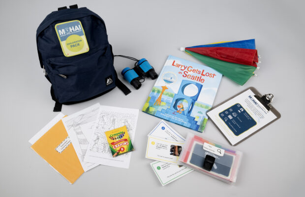 MOHAI Exploration Pack featuring Larry Gets Lost in Seattle book, binoculars, crayons, and other activities.