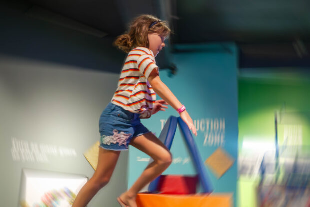 A child leaps through the air while playing in the Kid-Struction Zone at MOHAI.