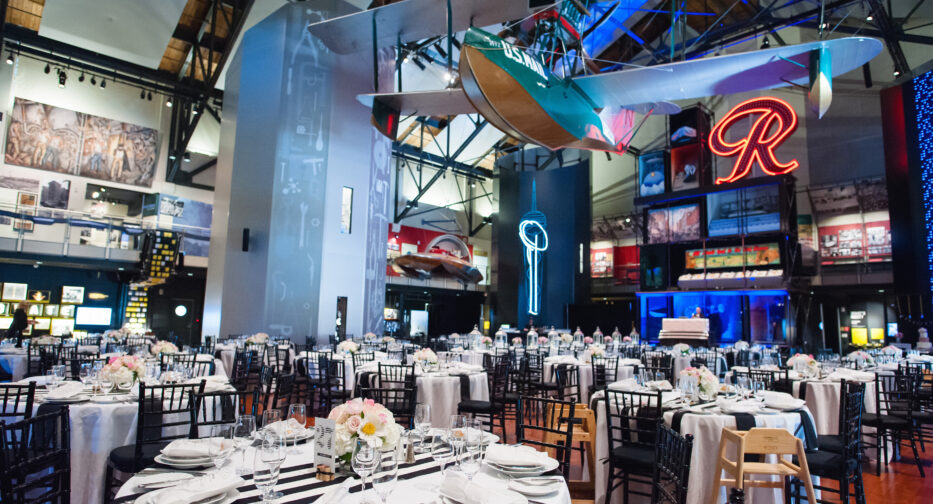 The Faye G. Allen Grand Atrium at MOHAI set up for an event with a farmhouse table. The Boeing B-1 hangs overhead. The Rainer 