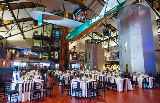 The Faye G. Allen Grand Atrium at MOHAI set up for an event with a farmhouse table. The Boeing B-1 hangs overhead.