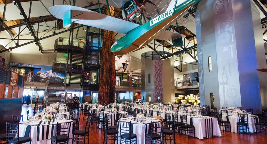 The Faye G. Allen Grand Atrium at MOHAI set up for an event with a farmhouse table. The Boeing B-1 hangs overhead.