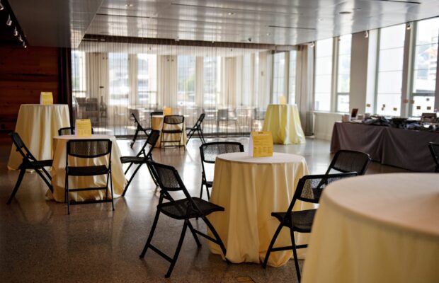 The Microsoft Lakefront Pavilion at MOHAI with small round tables covered in cream colored table cloths.