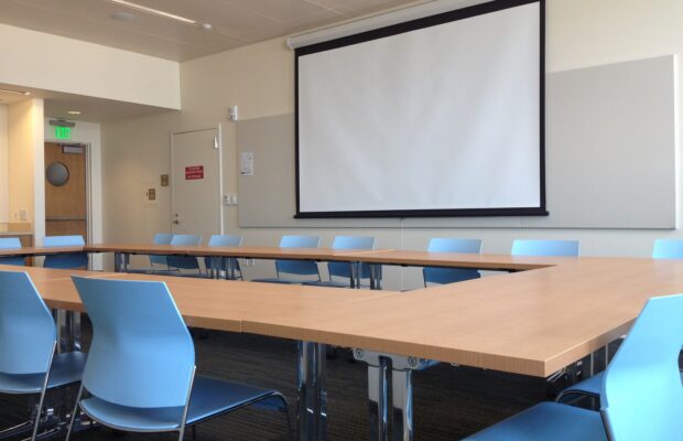 The Norcliffe conference room west shows movie screen, tables, and blue chairs.
