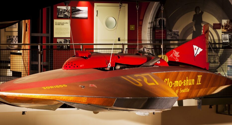 The hydroplane Slo-mo-shun IV hanging in the MOHAI Grand Atrium. The boat is wooden with red accents.