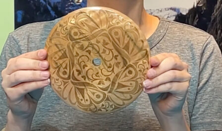 A Coast Salish spindle whorl used for spinning wool. The whorl has a variety of decorative carvings.