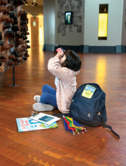 Girl looking through binoculars at the Wawona in the MOHAI Grand Atrium.