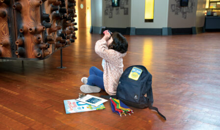 Girl looking through binoculars at the Wawona in the MOHAI Grand Atrium.