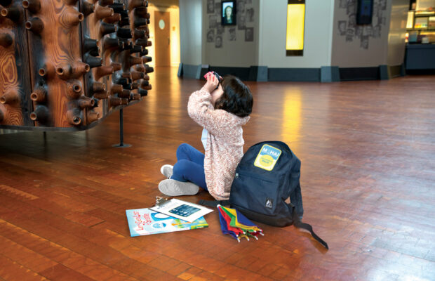 Girl looking through binoculars at the Wawona in the MOHAI Grand Atrium.