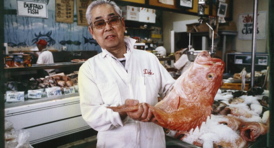 Dick Yoshimura, pictured here in 1984 in a white jacket holding a large fish, founded the Mutual Fish Company in 1947.