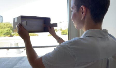 Person using portable camera obscura to look out of a window.