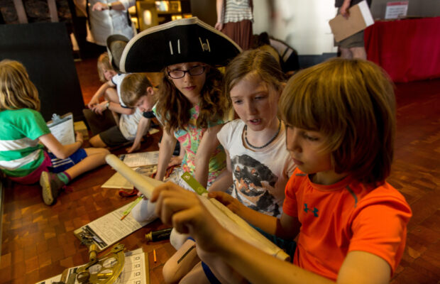 Children examining nautical items at MOHAI. One child wears a pirate hat.
