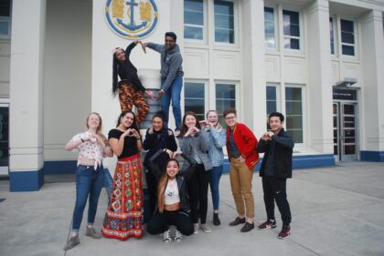 MOHAI Youth Advisors pose outside MOHAI making hearts with their hands and arms.