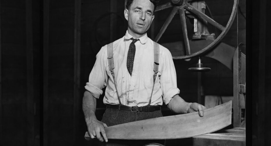 George Pocock posing for a photo with a piece of bent wood.