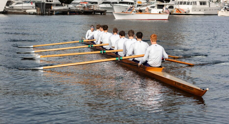 The University of Washington Men's Crew Team wearing white rowing the Husky Challenger on Lake Union in downtown Seattle.