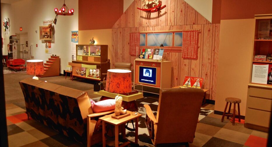 A living room from the 1950s complete with couch, rocking chair, and floor standing television.