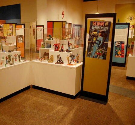 Toys of the '50s, '60s and '70s exhibit at MOHAI showing The Bride of Frankenstein poster adjacent to a display of action figures.