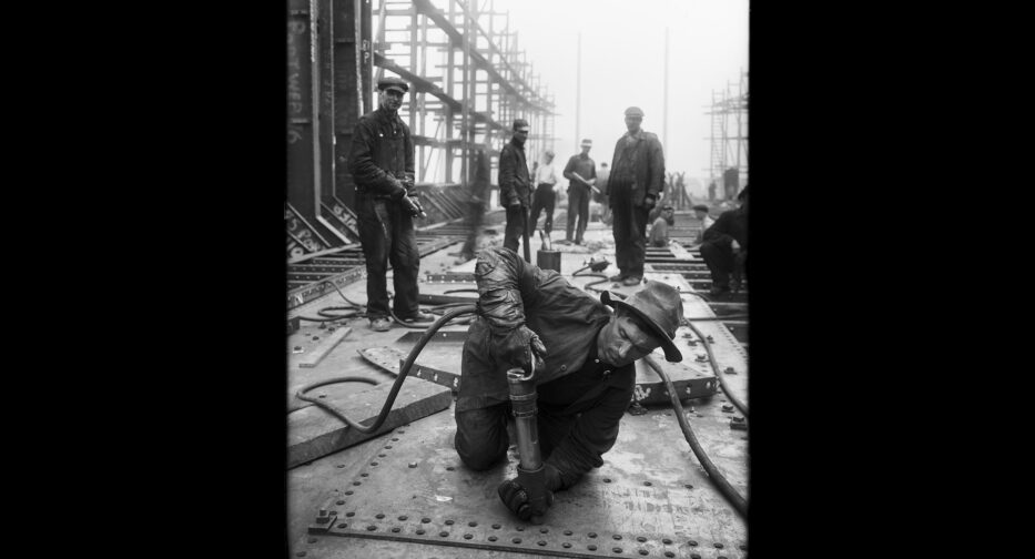 A shipyard riveter working with eight of his coworkers watching, September 1917.