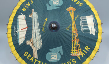 Green and yellow souvenir umbrella from Century 21, Seattle World's Fair, 1962. The Monorail, the Space Needle, the World of Science, and the Coliseum can be seen on the umbrella.