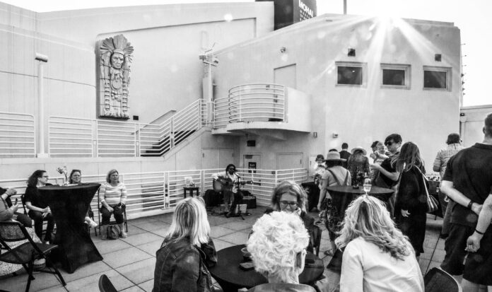 Black and white photo of Summer Nights on the Terrace attendees while Benjamin Hunter plays guitar and sing.