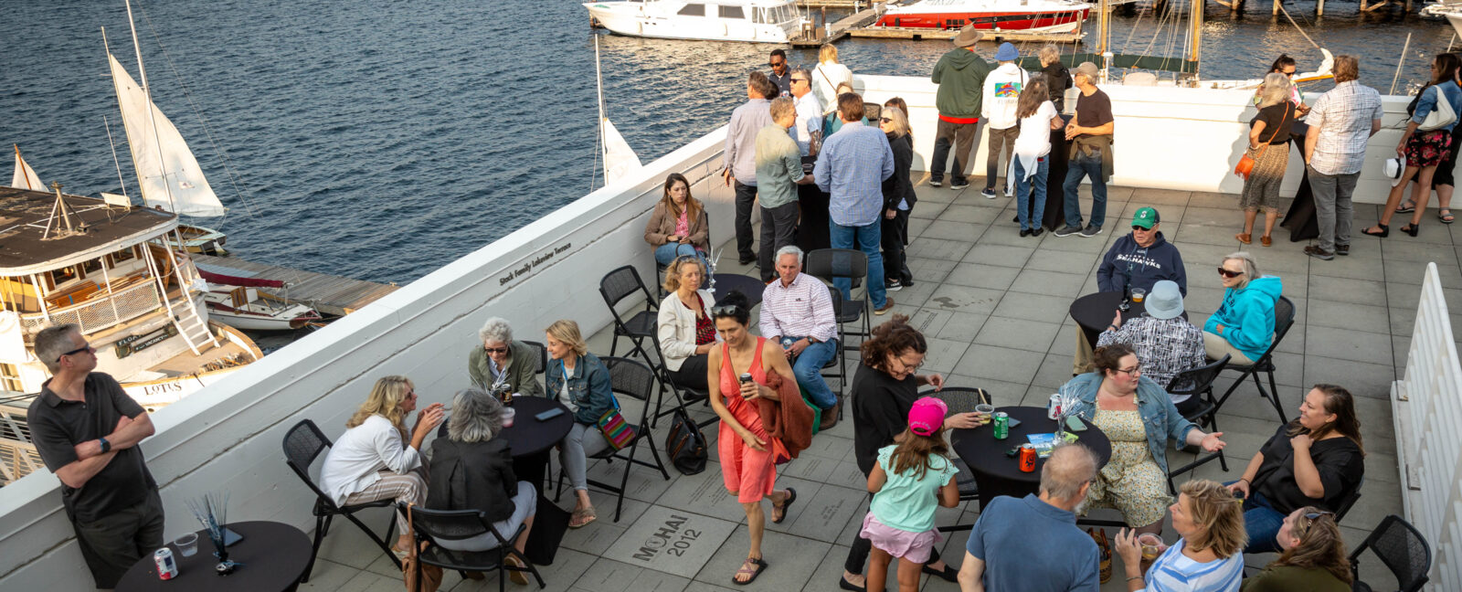 Summer Nights on the Terrace attendees in the foreground. Lake Union and docked boats in the background.