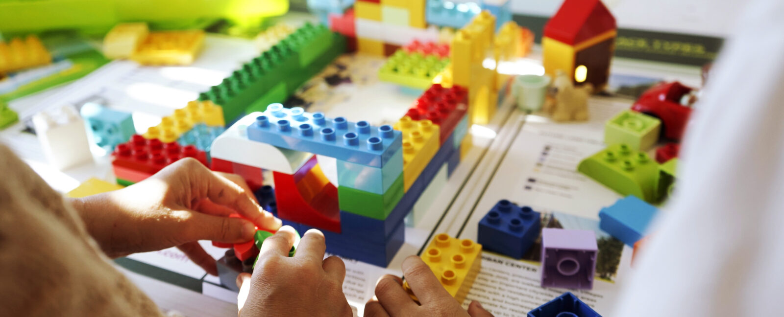 Hands manipulating colorful LEGO bricks.