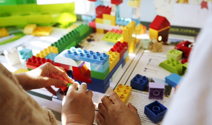 Hands manipulating colorful LEGO bricks.