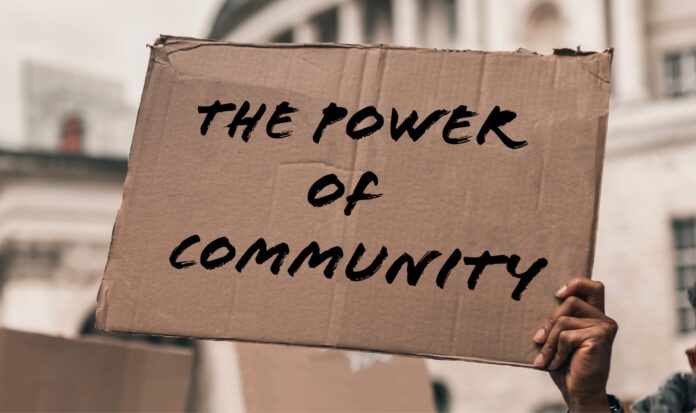 A single hand holding a cardboard sign that reads