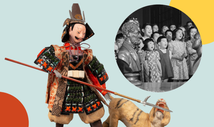 A doll in traditional Japanese armor fending off a tiger with a pike. Inset shows young school children singing adjacent to busy of Abraham Lincoln.