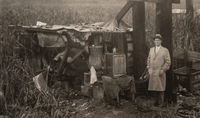 Mayor Robert Harlan standing by a shack at Hooverville