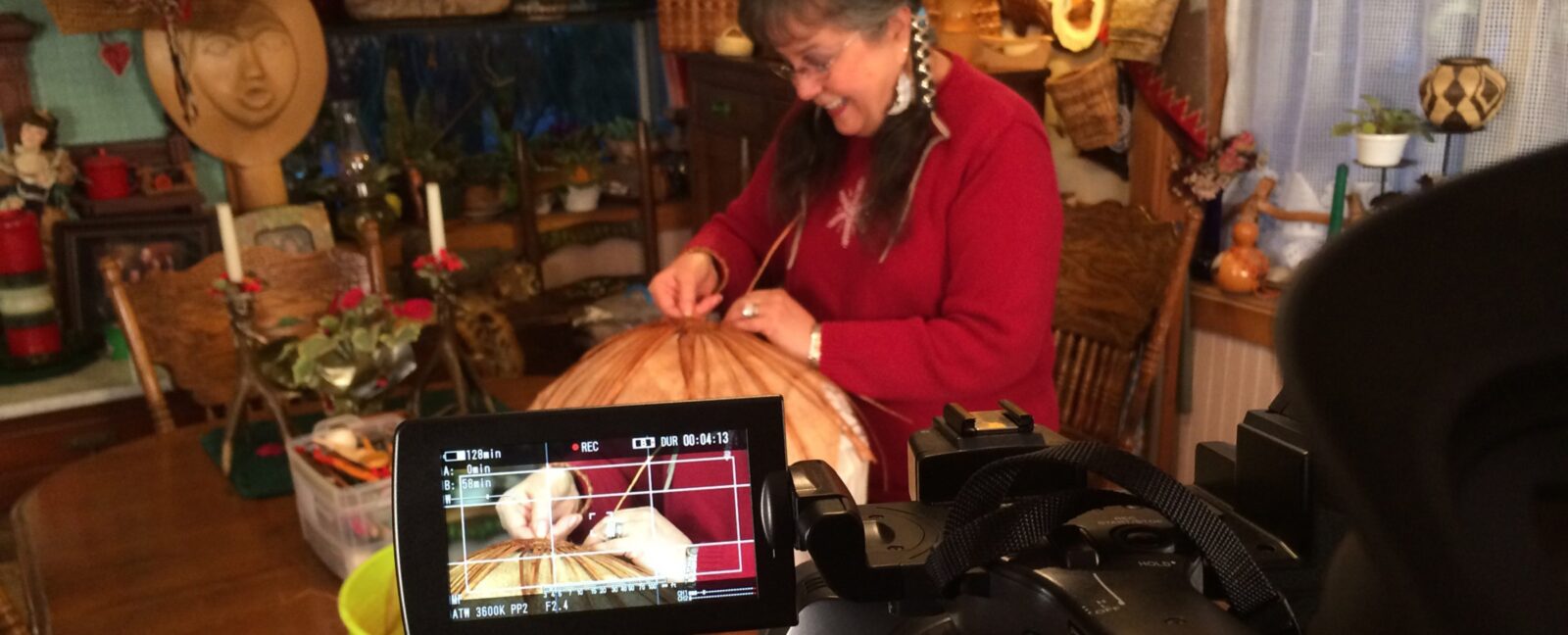Person in red sweater working on crafts while being filmed for the movie