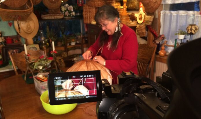 Person in red sweater working on crafts while being filmed for the movie