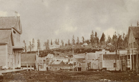 Commercial Street looking north showing a dirt street with a number of business fronts. Seattle, WA, 1865.