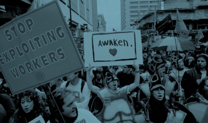 Activists marching in Seattle streets at the WTO protests of 1999. Visible signs read