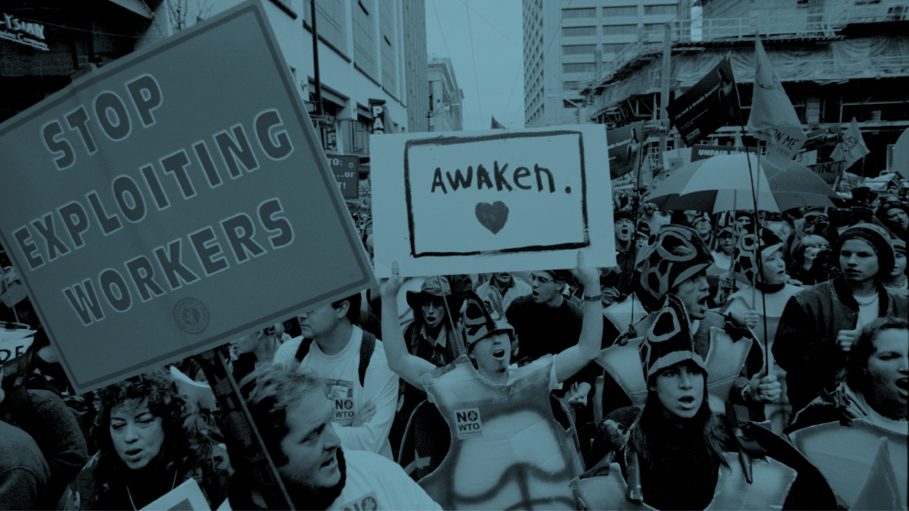 Activists marching in Seattle streets at the WTO protests of 1999. Visible signs read