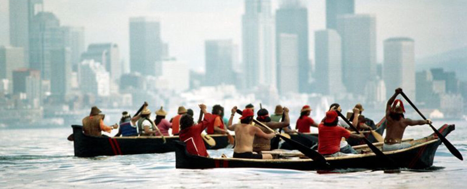 Two groups of indigenous peoples row two canoes across the Puget Sound near Seattle