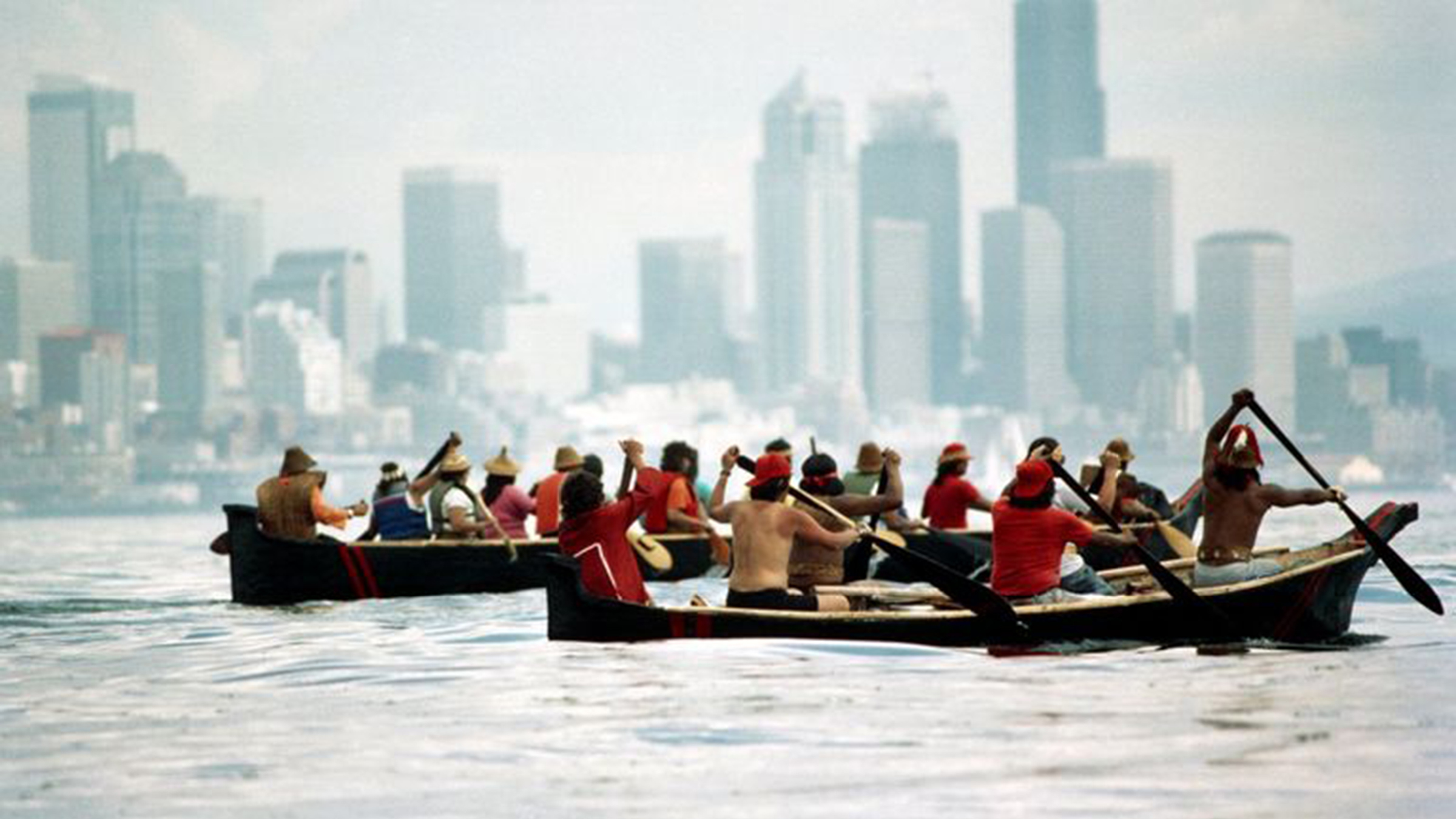 Two groups of indigenous peoples row two canoes across the Puget Sound near Seattle