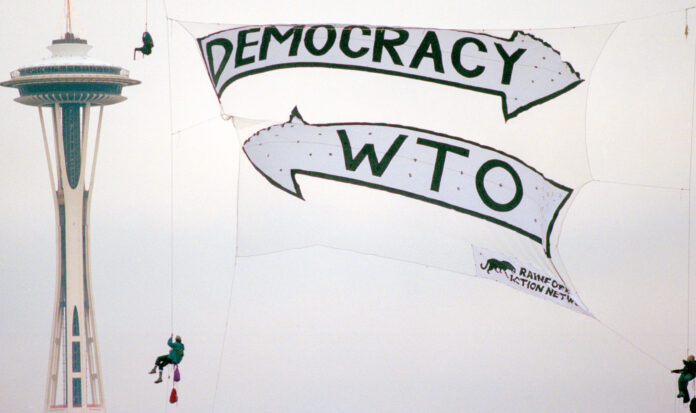 WTO protestors wearing turtle costumes march in downtown Seattle. A sign reads