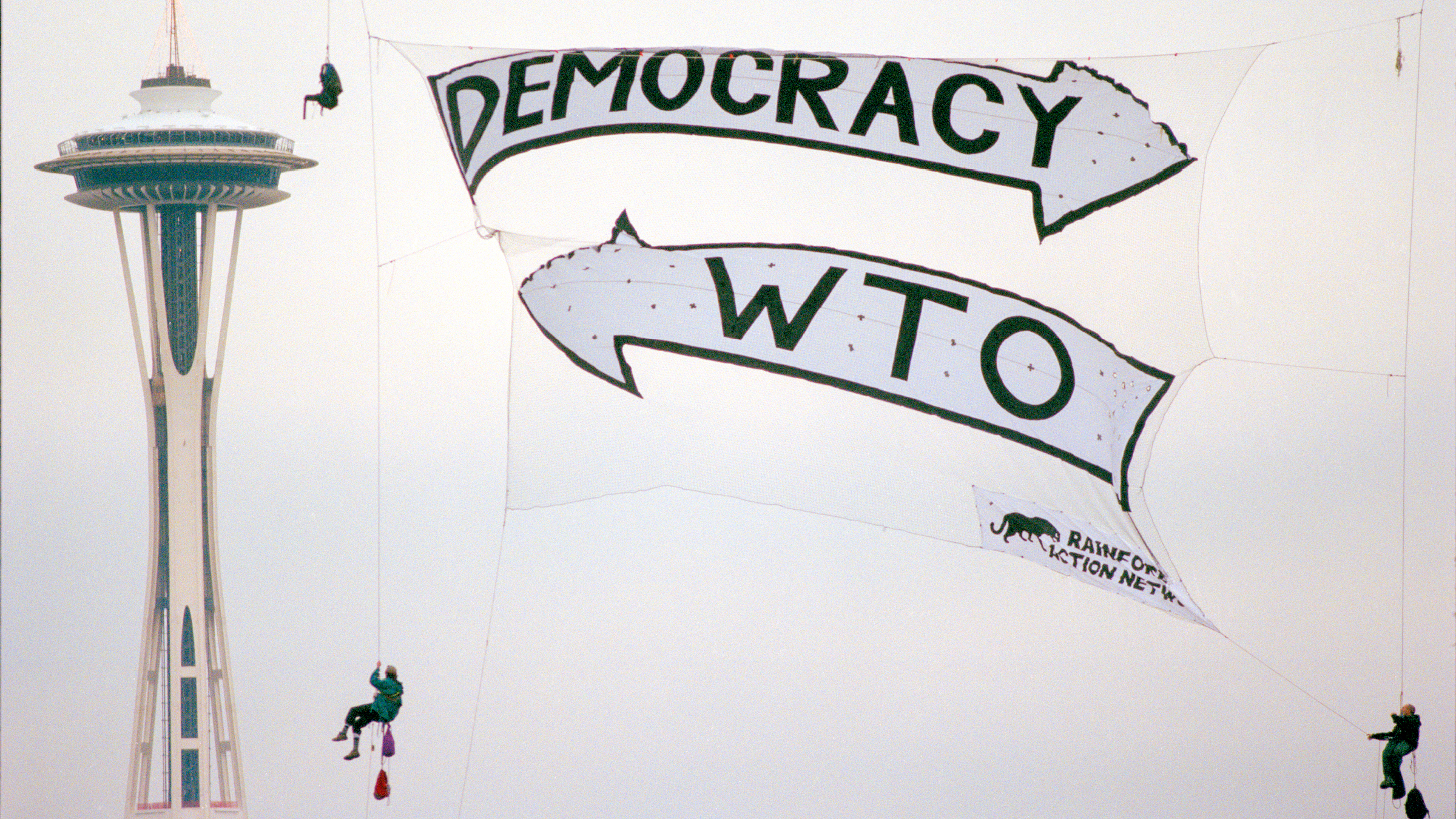 WTO protestors wearing turtle costumes march in downtown Seattle. A sign reads