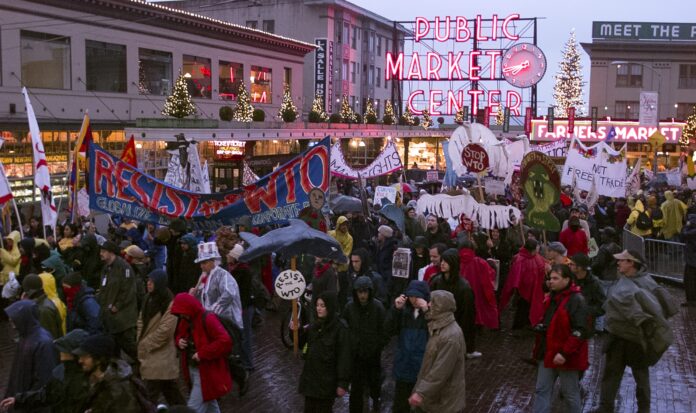 A crowd of protestors passing by the entrance to Pike Place Market.