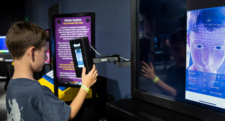 Boy having face digitally mapped onto screen.