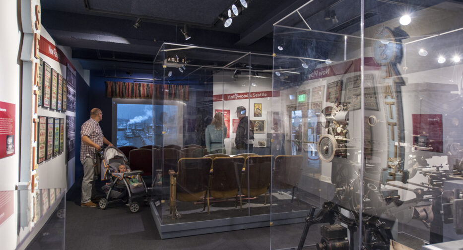 Visitors in Celluloid Seattle, with historic cameras in the foreground and a recreated theater in the background.