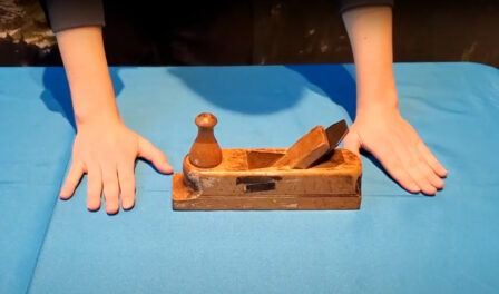 A wooden hand lathe displayed on a blue table.