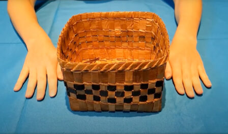 A traditional Coast Salish woven cedar basket displayed on a blue table.
