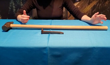 A sledge hammer and a railroad tie on a blue table.