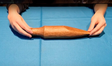 A traditional Salish wedge used for splitting wood displayed on a blue table.