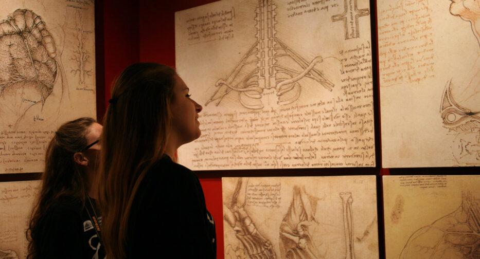 Two visitors viewing Leonardo da Vinci hand written notes at Da Vinci - Inventions Exhibit.