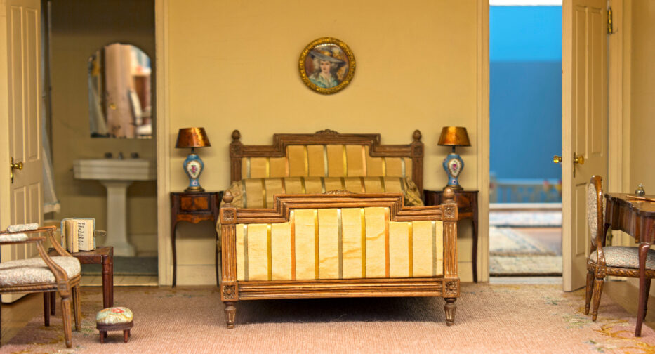 The interior of the Hammons House primary bedroom with bed, two chairs, a desk and a private bathroom.